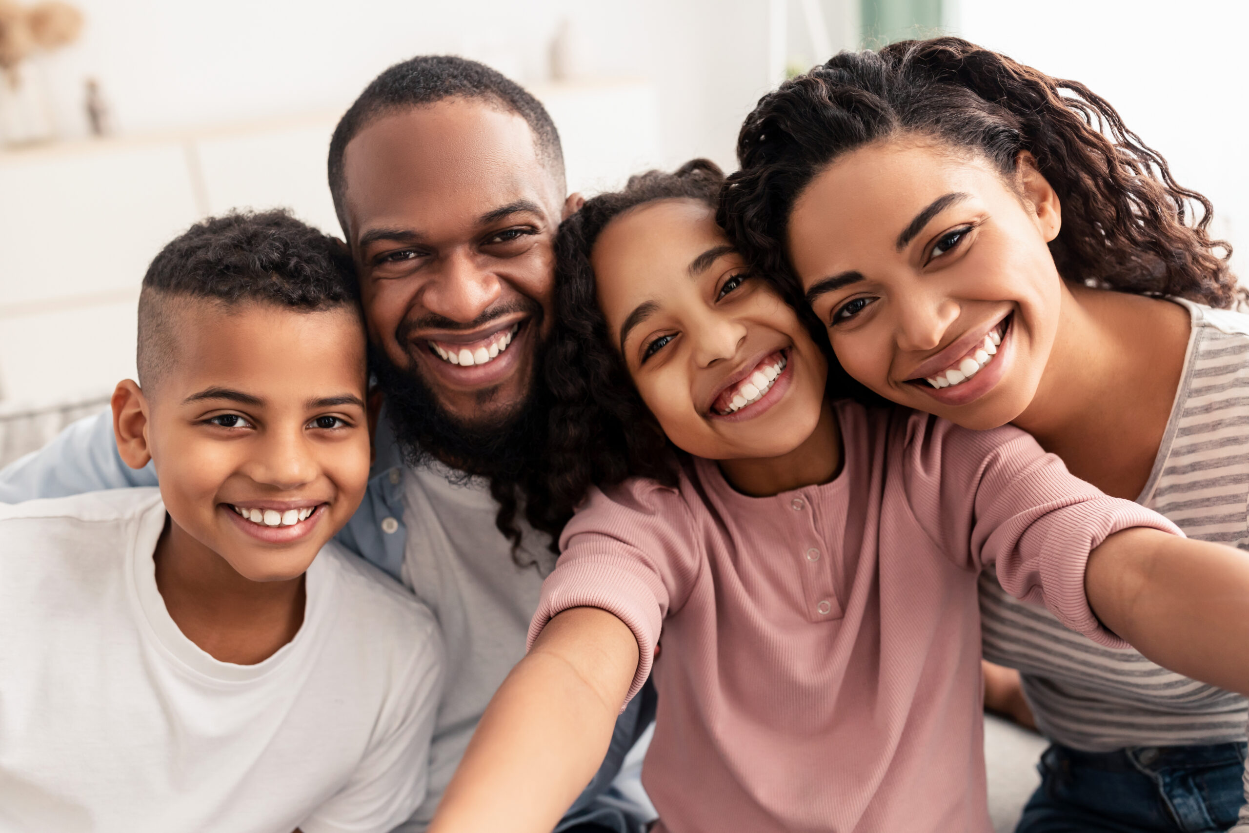 African-American family of 4 including father, mother, elementary school aged son and daughter all smiling